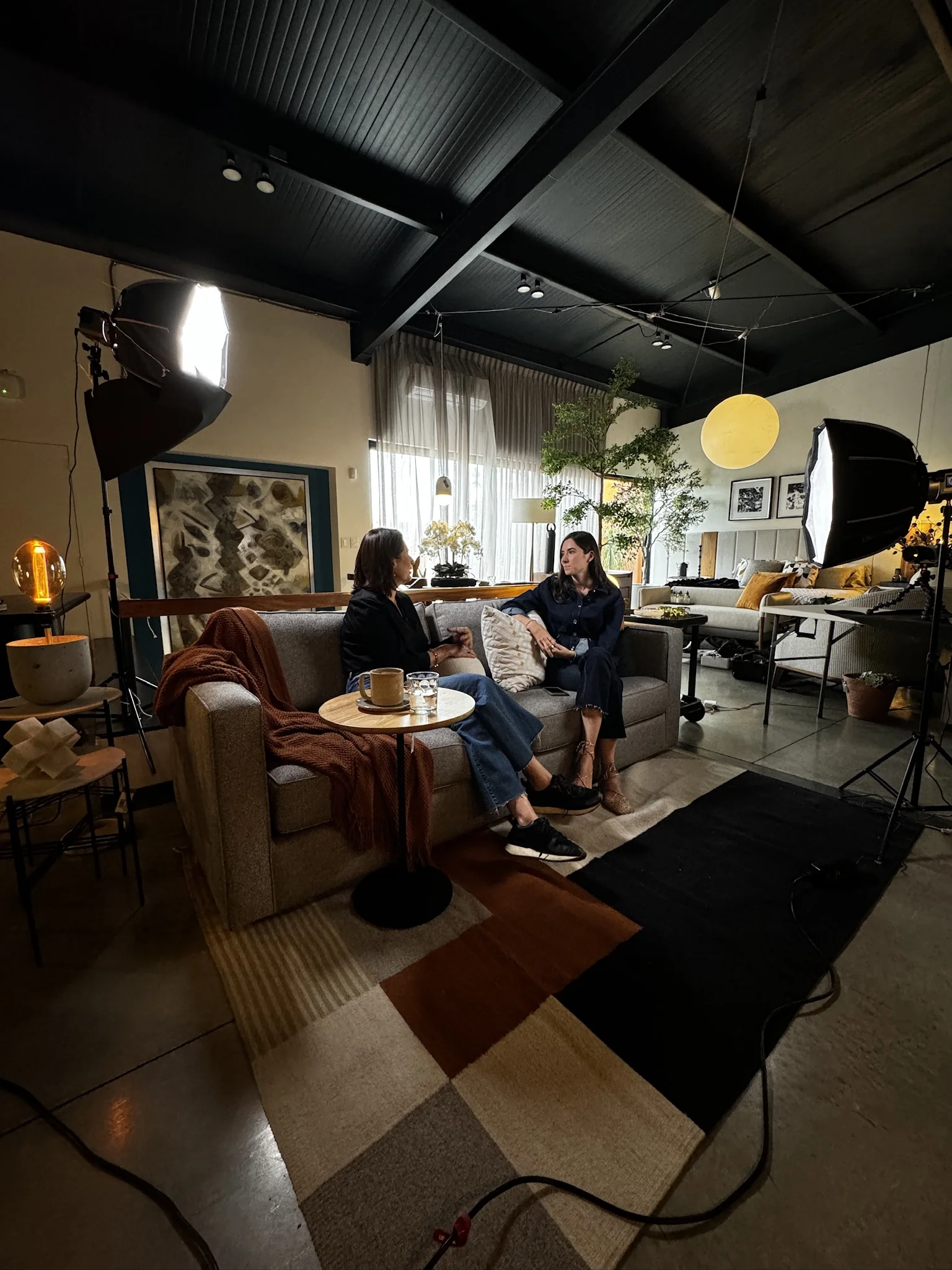 A conversation on the Amates sofa, with the filming lights and cameras in place