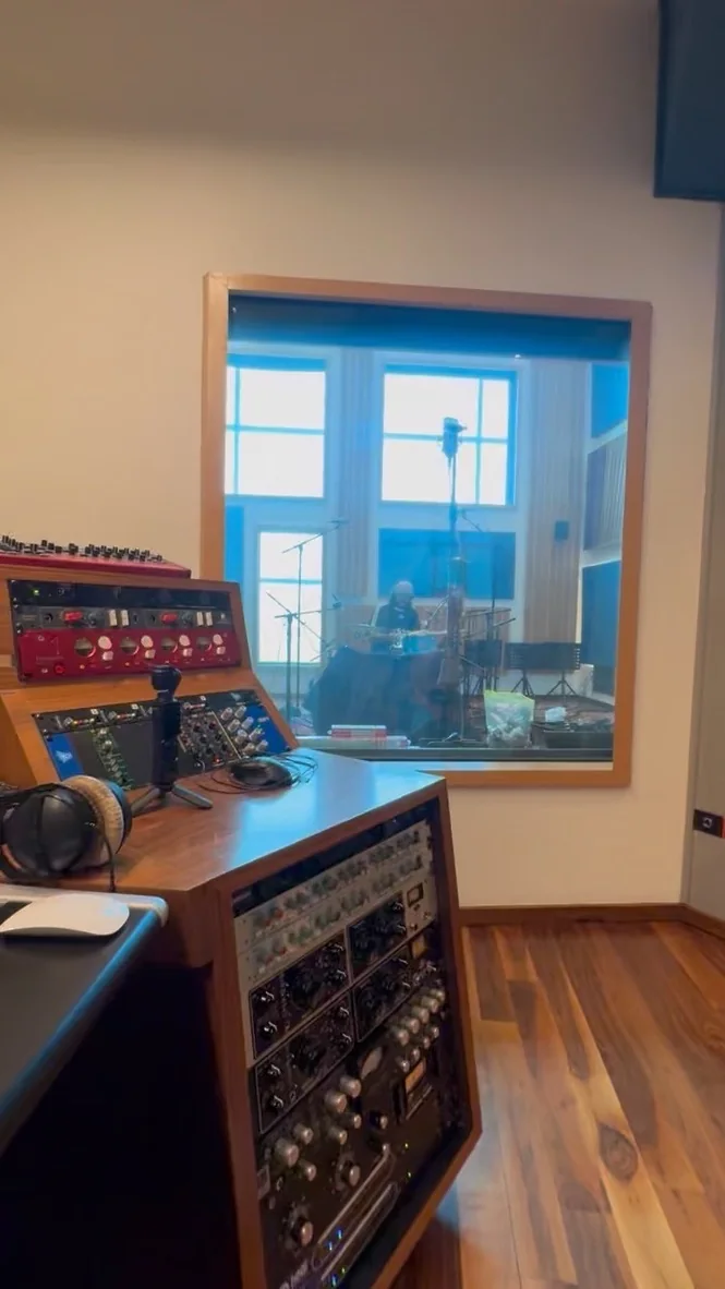 Chan recording drums at Estudio 13, seen through the control-room window